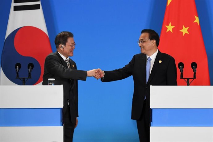 El presidente de Corea del Sur, Moon Jae In, y el primer ministro de China,  Li Keqiang, se saludan durante la cumbre que ambos países han mentenido junto a Japón en la ciudad china de Chengdú.