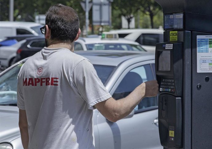 Un hombre al lado de un parquímetro en Madrid.