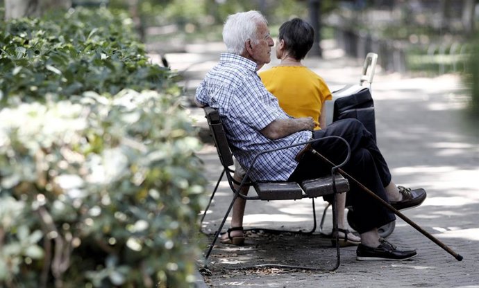 Un pensionista descansa en un banco de un parque de Madrid.