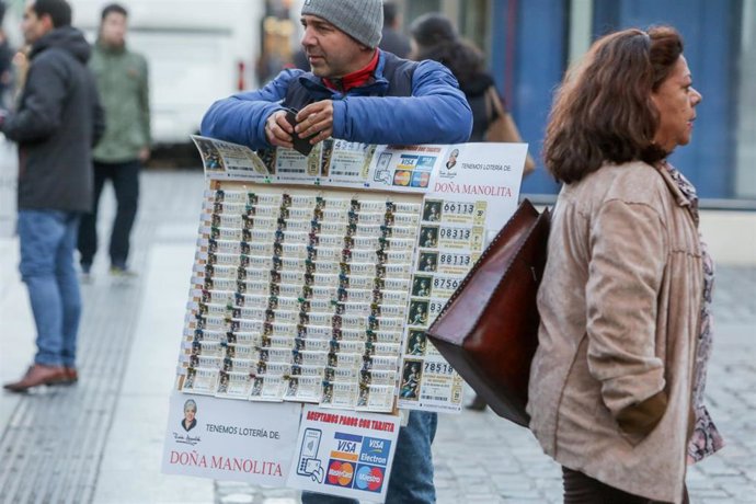 Un hombre vende décimos de Lotería de Navidad de la Administración de Doña Manolita, en Madrid (España), a 18 de noviembre de 2019.