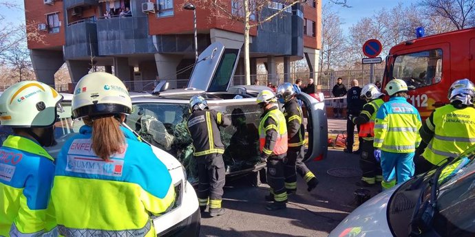 Bomberos de Fuenlabrada y personal del SUMMA 112 atienden a una mujer cuyo vehículo quedó semivolcado tras sufrir un accidente de tráfico.