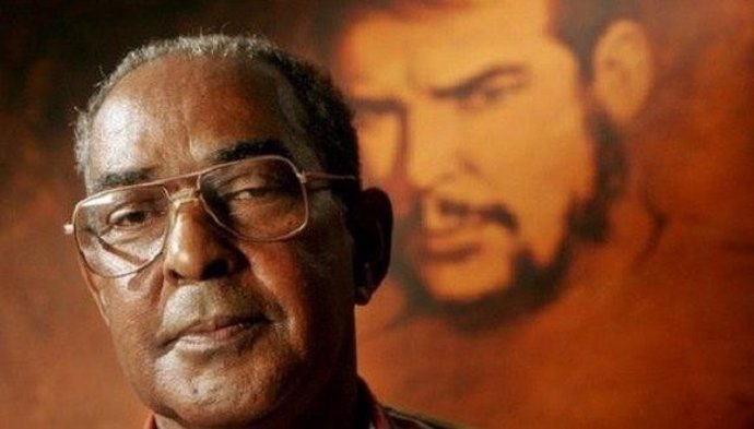 El revolucionario cubano Harry Villegas delante de un retrato de Ernesto Che Guevara