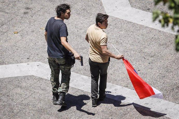 Un manifestante a favor del exdictador chileno Augusto Pinochet apunta con un arma a viandantes en el centro de Santiago de Chile durante una manifestación en apoyo a Carabineros.