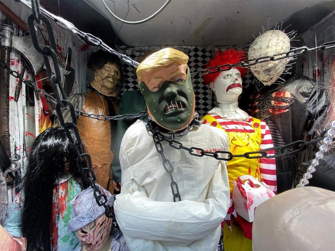 Un escaparate de una tienda de disfraces con personajes de miedo y villanos de películas, a un día de la noche de Halloween.