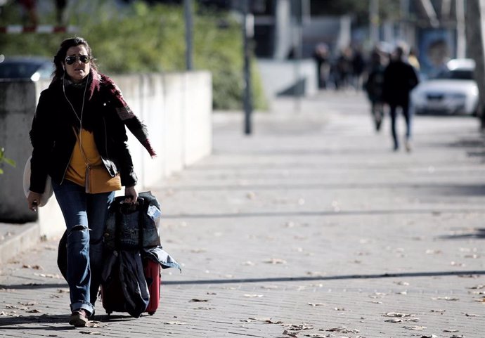 Una mujer camina con su maleta por una calle