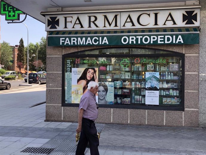 Personas caminan alrededor de una Farmacia en Madrid.