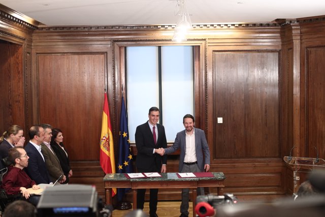 El presidente del Gobierno en funciones, Pedro Sánchez (izq) y  el secretario general de Podemos, Pablo Iglesias (dech), se dan la mano durante el acto de presentación del programa de Gobierno del PSOE y Unidas Podemos, en el Congreso.