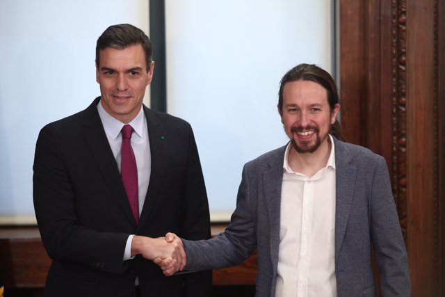 El presidente del Gobierno en funciones, Pedro Sánchez (izq) y  el secretario general de Podemos, Pablo Iglesias (dech), se dan la mano durante el acto de presentación del programa de Gobierno del PSOE y Unidas Podemos, en el Congreso.