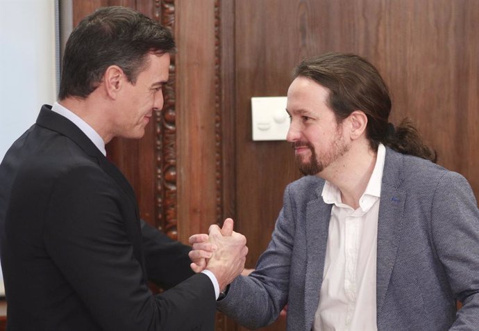 El president del Govern en funcions, Pedro Sánchez (esq) i el secretari general de Podemos, Pablo Iglesias (dr), es donen la m durant l'acte de presentació del programa de Govern del PSOE i Unides Podem, al Congrés dels Diputats, Madrid (Espanya).