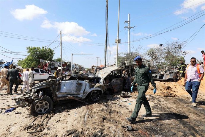 Un oficial de la Policía somalí pasa por la escena del atentado con coche bomba perpetrado por el grupo terrorista Al Shabaab, en Mogadiscio.