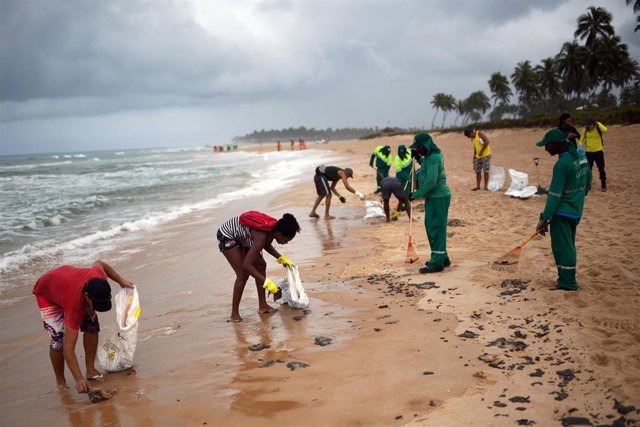 Empleados municipales y voluntarios trabajan para retirar manchas de petróleo en una playa de Camacari, municipio de Bahía, en el oeste del país.