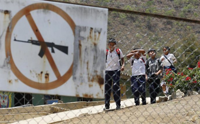 Escolares colombianos caminan detrás de una señal que prohíbe portar armas en un colegio de Toribío, en el oeste de Colombia.