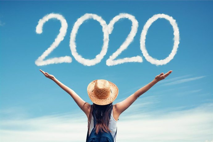 Woman with hat greets the 2020 against clouds