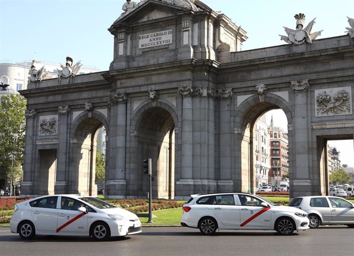 Imagen de recurso de varios taxis a su paso por la Puerta de Alcalá, en la ciudad de Madrid.