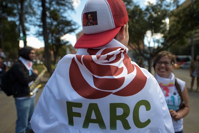 Un hombre con una bandera del partido FARC