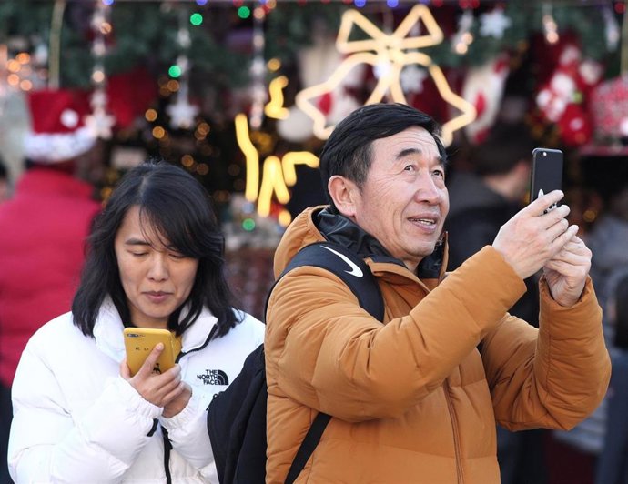 Un hombre toma una foto con su movil de uno de los puestos del mercadillo de Navidad de la Plaza Mayor de Madrid.