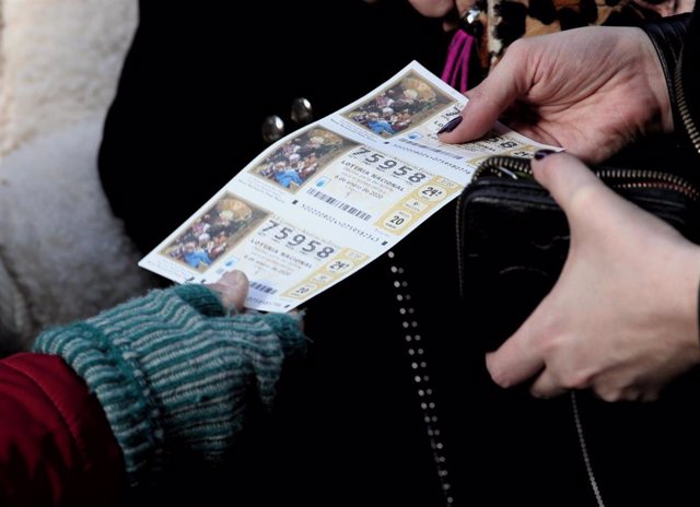 Una mujer compra varios boletos de la Lotería del Niño.
