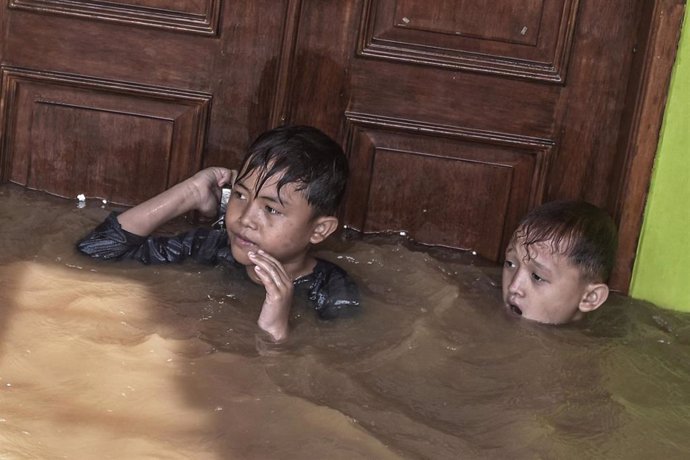 Dos niños se mantienen a flote en una de las áreas inundadas tras las violentas lluvias caídas en varios puntos de Indonesia.