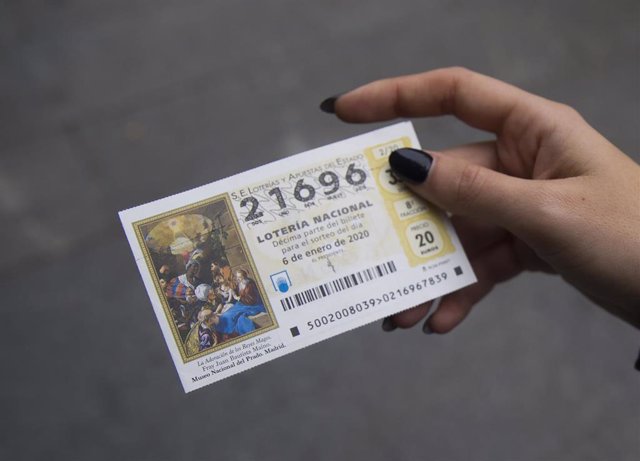 Una mujer muestra su numero de boleto de la lotería del Niño. 