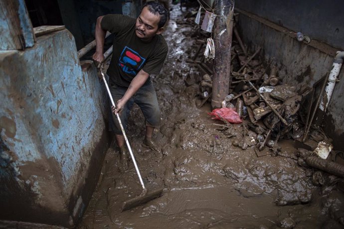 Un hombre intenta limpiar su casa del lodo provocado por las fuertes lluvias caídas en Yakarta, Indoensia, desde Año Nuevo (2020).