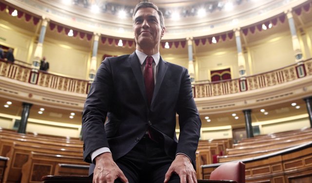 El presidente del Gobierno, Pedro Sánchez, posa sonriente en el hemiciclo del Congreso de los Diputados, tras obtener una votación favorable a su investidura.