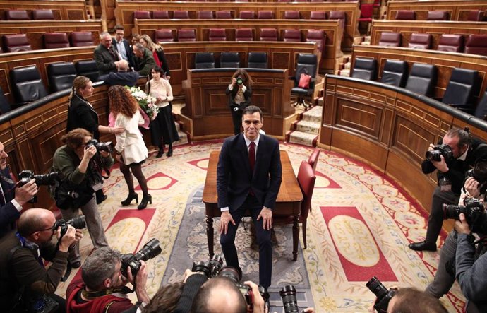 El presidente del Gobierno, Pedro Sánchez, posa sonriente en el hemiciclo del Congreso de los Diputados, tras obtener una votación favorable a su investidura 