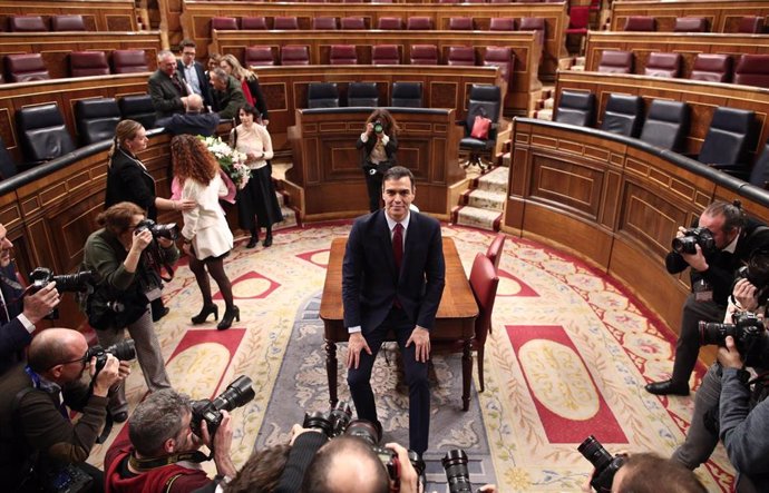 El presidente del Gobierno, Pedro Sánchez, posa sonriente en el hemiciclo del Congreso de los Diputados, tras obtener una votación favorable a su investidura 
