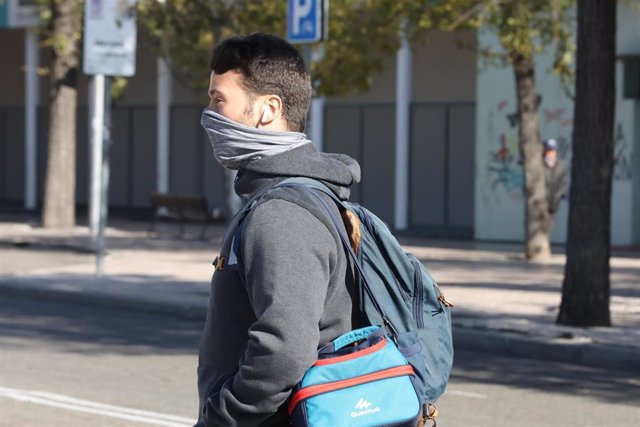Un joven se abriga la cara, protegiéndose del frío, durnate un día de viento por Madrid (España), a 8 de noviembre de 2019.