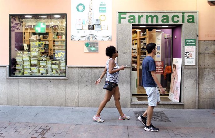 Una pareja cruza por delante de la puerta principal de una farmacia.