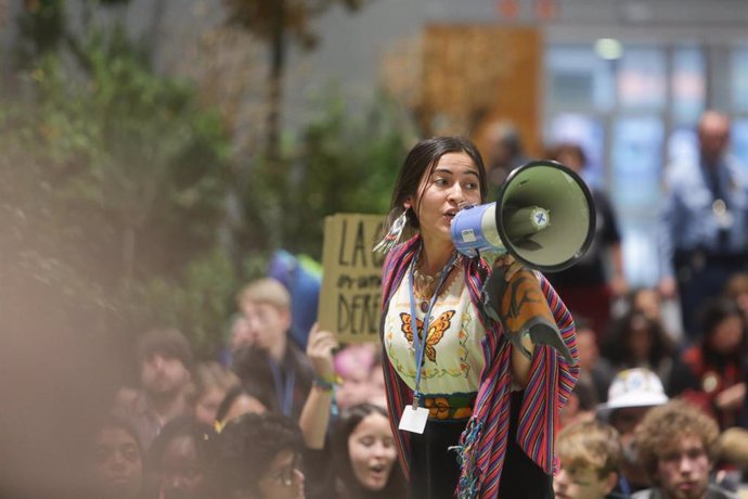 Una activista del movimiento Fridays for Future habla a través de un megáfono durante una sentada en el pabellón 4 en protesta por los resultados "insuficientes" logrados en la Cumbre del Clima (COP25) que se celebra hasta hoy en Ifema, Madrid (España),