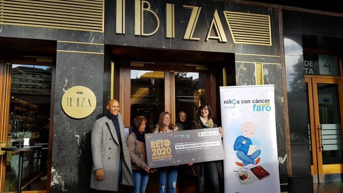 El socio y gerente de Café Ibiza, David Houngbeme, entrega en un cheque lo recaudado en el vermú solidario a FARO