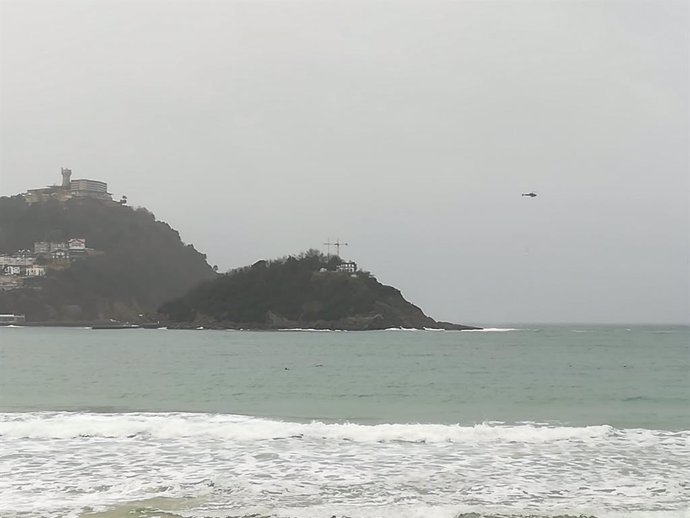 Un helicóptero traslada material de la casa del faro desde la isla al Paseo Nuevo de San Sebastián