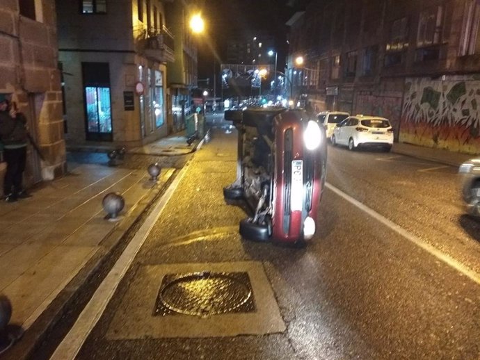 Coche volcado en la calle Falperra de Vigo, cuyo conductor dio positivo en alcoholemia y fue denunciado por un supuesto delito contra la seguridad vial.