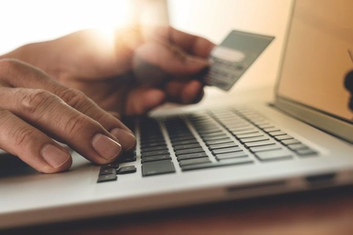 Acode usando un computador con cartón de crédito e facendo compras online
