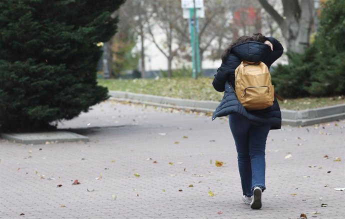 Una mujer caminando por la calle se protege del viento durante el peor temporal del otoño del 2019 en España en el que se verán afectadas 37 provincias avisadas por viento, nieve, oleaje o lluvia, en Madrid a 14 de noviembre de 2019.
