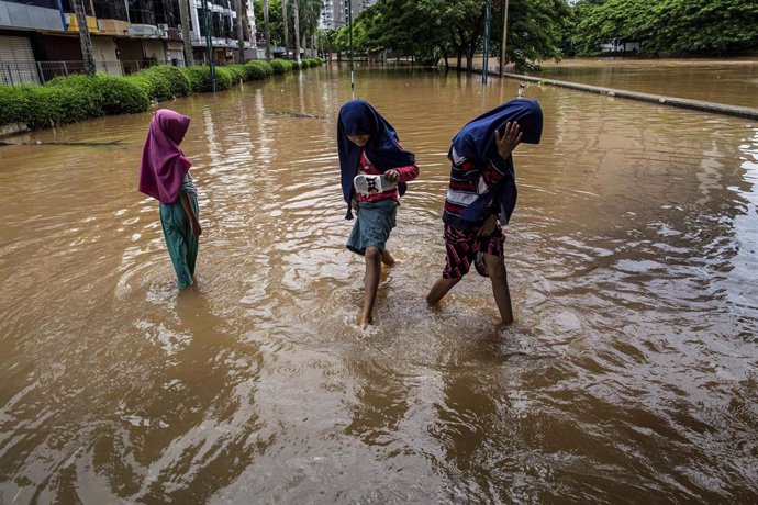 Tres niñas caminan sobre las calles inundadas de Yakarta tras las precipitaciones que cayeron sobre la capital de Indonesia a principios de enero de 2020.
