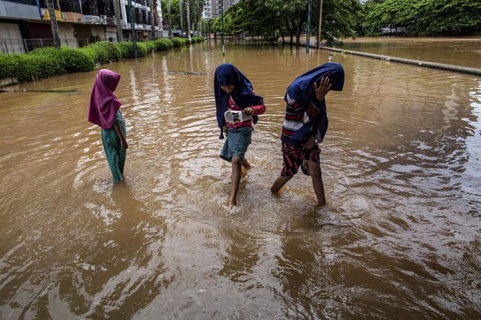 Tres nenes caminen sobre els carrers inundats de Jakarta després de les precipitacions que van caure sobre la capital d'Indonsia a principis de gener del 2020 (Arxiu)