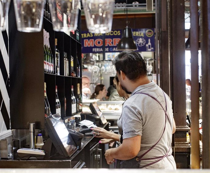 Dos camareros cobran las cuentas de los clientes en un bar de Madrid.
