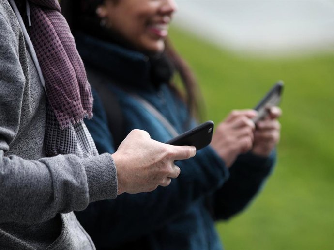 Dos personas hacen uso de sus móviles durante uno de los días que los operadores recopilaron datos de posicionamiento anonimizados y agregados para el estudio de movilidad del INE 