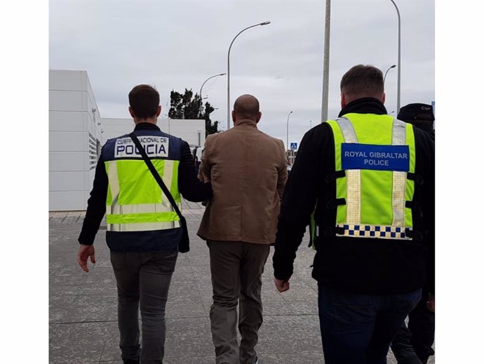 Agentes de la Policía Real de Gibraltar y de la Policía Nacional de España, acompañando a uno de los dos acusados de trata de personas