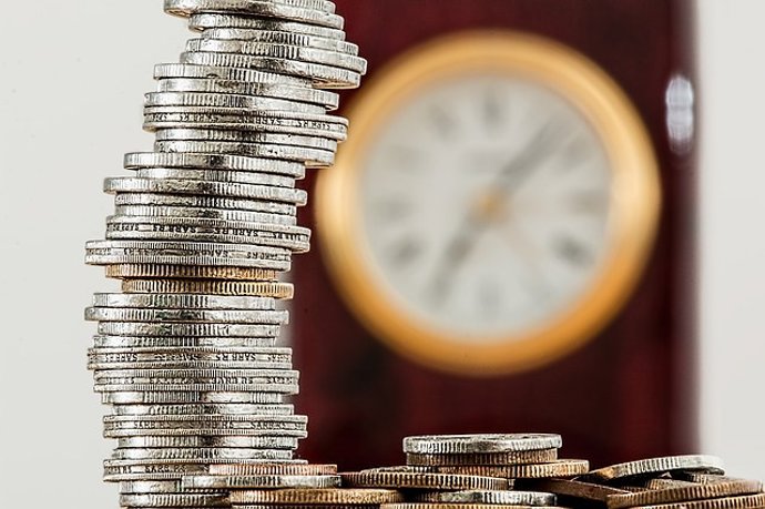 Monedas apiladas delante de un reloj