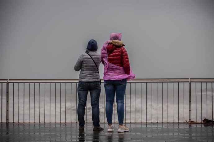 Dos mujeres en el paseo marítimo de Barcelona, donde la borrasca 'Gloria' ha dejado fuertes rachas de viento y lluvia, a 21 de enero de 2020.