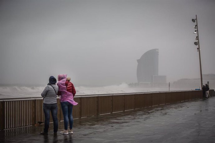 Dos mujeres en el paseo marítimo de Barcelona, donde la borrasca 'Gloria' ha dejado fuertes rachas de viento y lluvia, a 21 de enero de 2020.