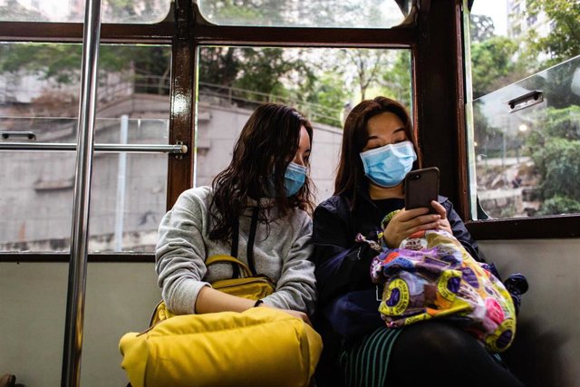 China deaths from coronavirus infection increase to 80 Dos mujeres en el transporte público de Hong Kong usando las mascarillas que el Gobierno de China ha recomendado utilizar debido a la rápida propagación dle coronavirus.