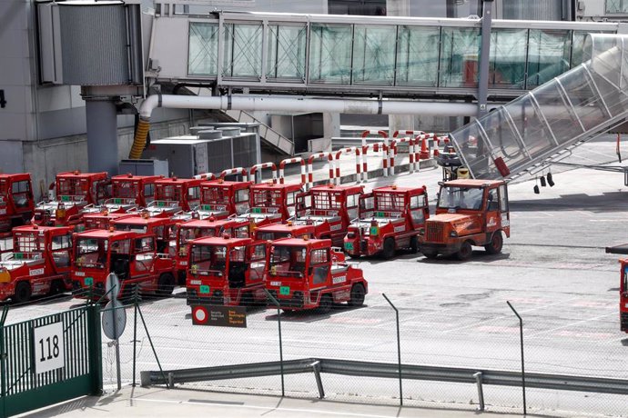 Gruas de transporte de equipaje estacionadas en las pistas de un aeropuerto.