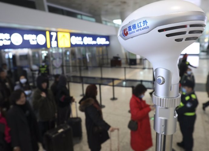 Personal del Aeropuerto Internacional de Tianhe en Wuhan (China) toma la temperatura a pasajeros.