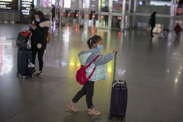 January 27, 2019 - Nanning, China: A young girl in a surgical face mask near the the exit gate after arriving on high speed train that departed from Shanghai ten and a half hours earlier