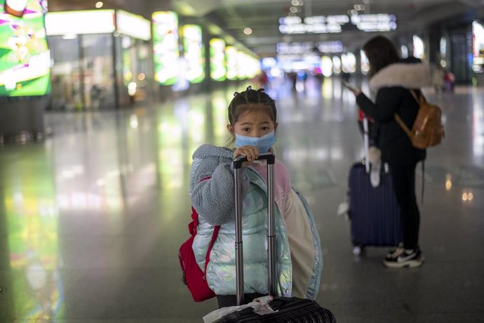 January 27, 2019 - Nanning, China: A young girl in a surgical face mask near the the exit gate after arriving on high speed train that departed from Shanghai ten and a half hours earlier.