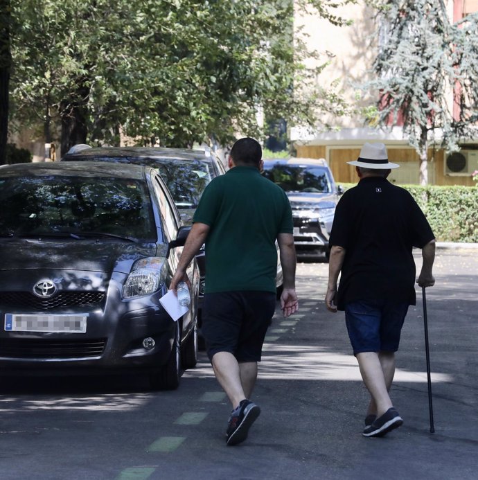 Un hombre pasea junto a un anciano por una calle de Madrid.