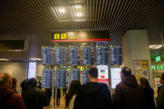 Varias personas comprueban la llegada de vuelos en varios paneles luminosos en el inicio de la operación salida de Navidad en el aeropuerto Adolfo Suárez Madrid-Barajas, en Madrid a 20 de diciembre de 2019.